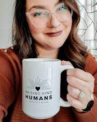 Happy as a mother Erica Djossa holding a mug that says "raising kind humans"